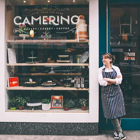 caryna camerino leans against the doorways of camerino bakery