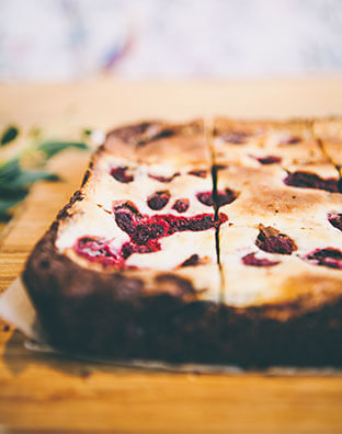 a close up shot of raspberry cheesecake brownies on a wooden board