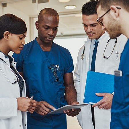 doctors and healthcare workers in white coats and blue scrubs gather to look at a chart some come from abroad for job opportunities