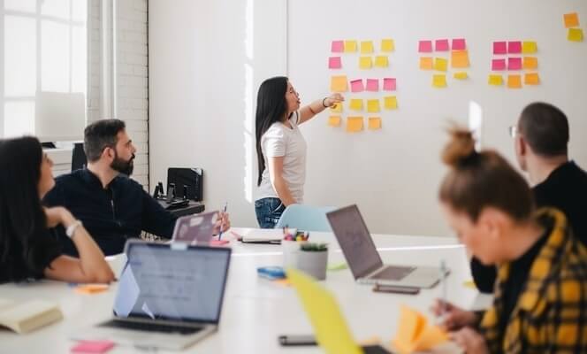 Woman standing at board with postits leads business meeting