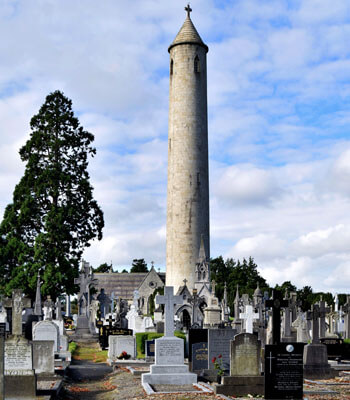 stone round tower stands above grave stones at glasnevin cemetery