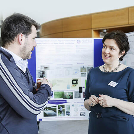 professor fiona regan wears a name tag and chats with audience member