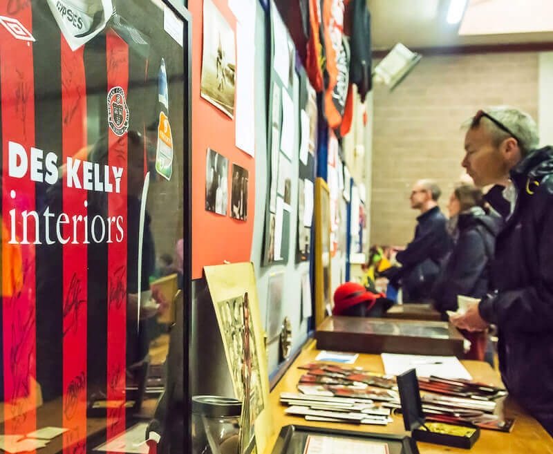 visitors looks at artefacts, including photos, frames and a bohemians jersey