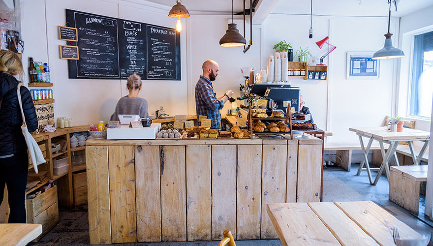 two people work behind the wooden counter at two pups coffee, francis street