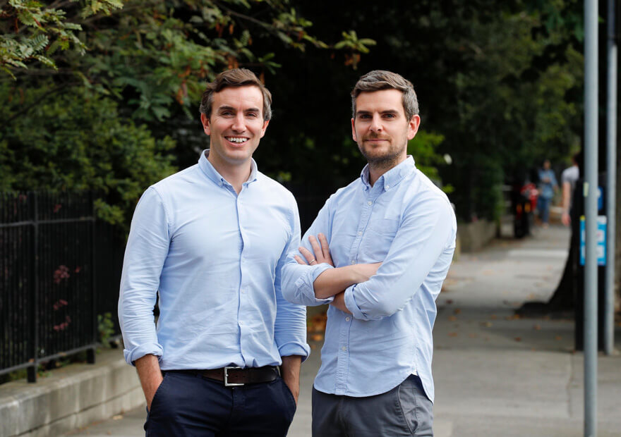 brothers john and stephen quinn stand side by side on a tree-lined street in dublin