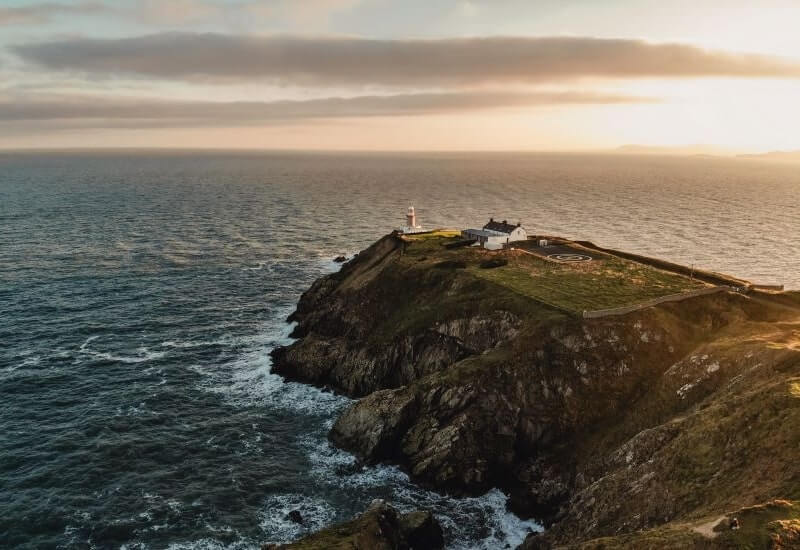 sun shines over sea and cliffs at howth beacon