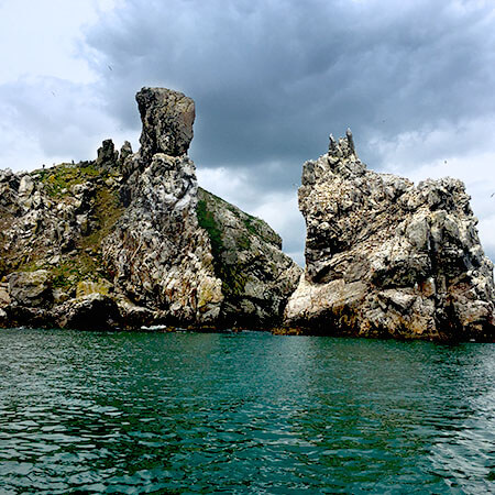 the cliffs at ireland's eye stand high above the green water