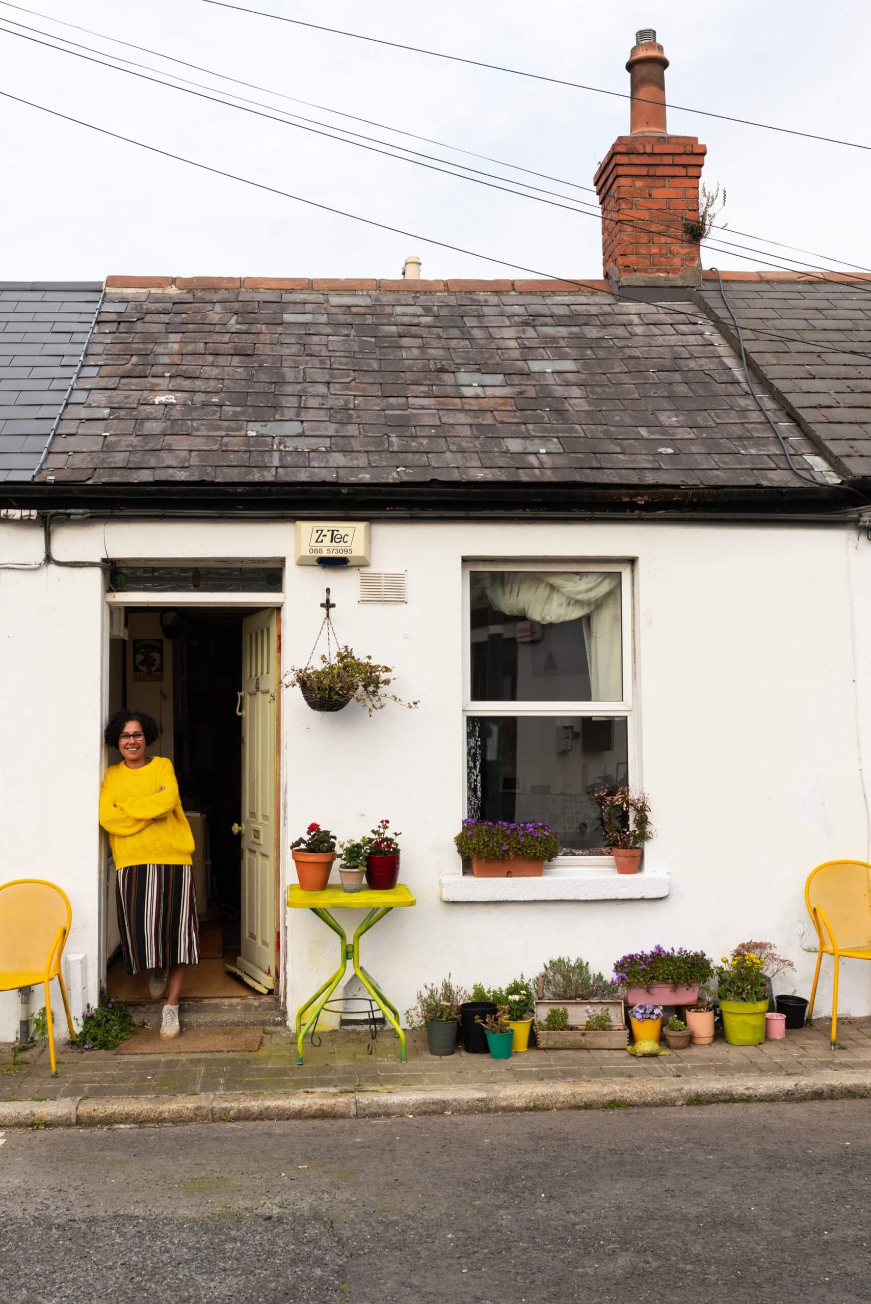 A woman in a yellow jumper leans against her open door