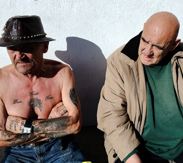 two male swimmers sit in the sun at dublin's forty foot