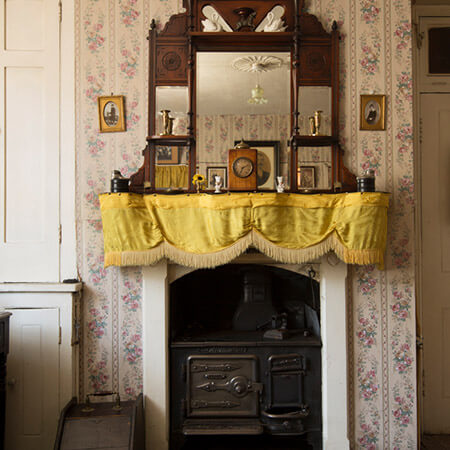 a cast iron range sits below the fireplace